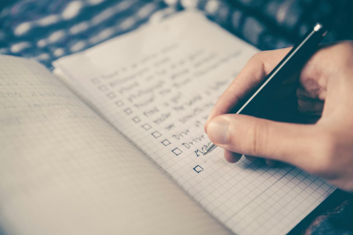 Person writing notes in a notebook with a pen